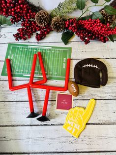 sports themed cookie cutters and decorations on a white wooden table with red berries, pine cones, and football