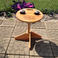 a wooden table sitting on top of a patio next to purple flowers and a fence