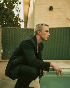 a man kneeling down next to a swimming pool