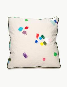 a white pillow with multicolored paint splattered on it's side