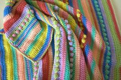 a multicolored crocheted blanket laying on top of a table