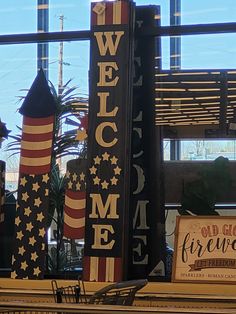 a welcome sign is displayed in front of a window with an american flag on it