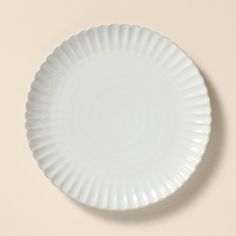 a white paper plate sitting on top of a beige table next to a brown wall