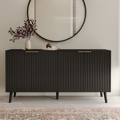 a black sideboard with a round mirror above it