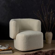 a white chair sitting on top of a floor next to a vase filled with flowers