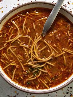 a bowl of soup with noodles in it and a spoon sticking out of the top