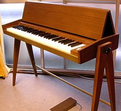 a wooden piano sitting on top of a hard wood floor next to a glass window