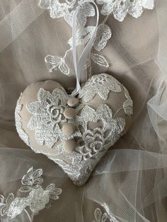 a heart shaped ornament with white lace on it sitting on top of a bed