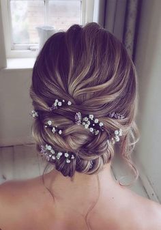 the back of a woman's head with flowers in her hair, looking out a window