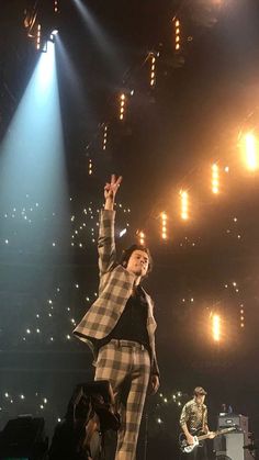 a man standing on top of a stage with his hands in the air