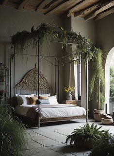 a bedroom with a canopy bed and potted plants on the floor next to it