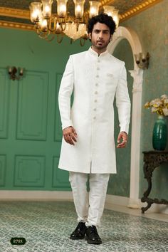 a man in a white sherve with black shoes and a chandelier