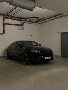 a black sports car parked in a garage with red piping on the ceiling and white walls