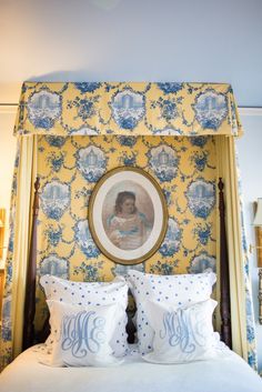 a bed with blue and yellow wallpaper in a bedroom next to a painting on the wall