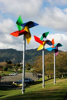 three colorful windmills are in the middle of a grassy area