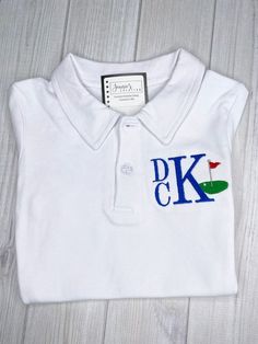 a white polo shirt with the letters pk and k in blue, green, red, and white on it