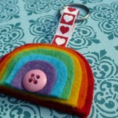 a keychain with a button on it and a rainbow in the middle, sitting on top of a table