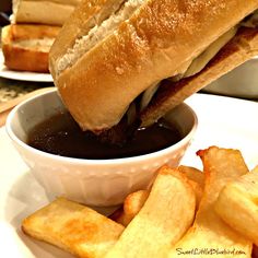 a sandwich and some fries on a white plate with sauce in a bowl next to it