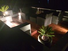 a potted plant sitting on top of a wooden table next to chairs and lights