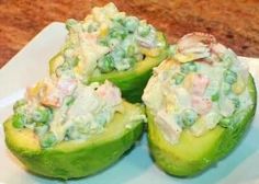 three stuffed cucumbers on a white plate with green beans and other toppings