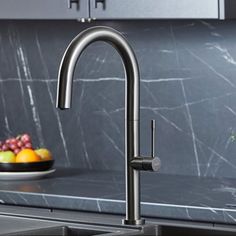 a kitchen sink with a bowl of fruit on the counter