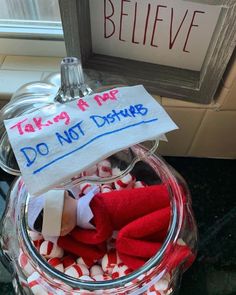 a glass jar filled with candy canes next to a sign that says take a nap do not disturb