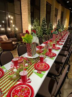 a long table set for christmas dinner with red and green plates, napkins and cups