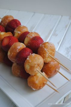 strawberries and sugar coated donuts are arranged on skewers