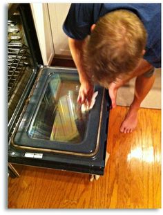 a man bending over to look inside an oven with the door open and food in it