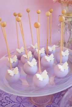 there are some cake pops on the plate and one is purple with white butterflies in it