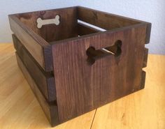 a wooden crate sitting on top of a table with a bone in it's mouth