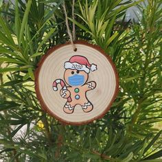 a wooden ornament hanging from a tree with a santa hat on it's head