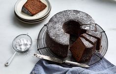 a chocolate cake on a wire rack with powdered sugar and spoons next to it