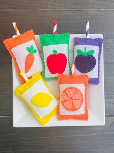 four felt fruit and veggie appetizers on a white plate with two straws