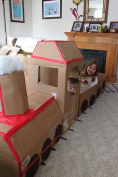 two children are playing in a cardboard train