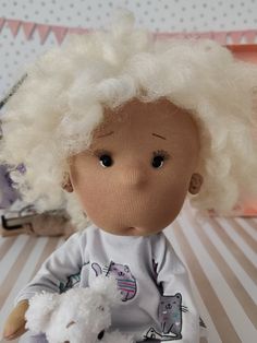 an old doll with white hair holding a teddy bear on a striped tablecloth background