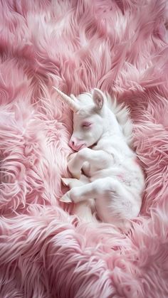 a baby unicorn sleeping on top of a pink fluffy blanket in the shape of a ball