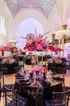 the tables are set with black linens and pink flowers in tall centerpieces