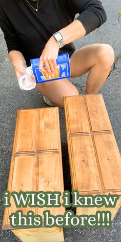 a woman sitting on the ground next to two pieces of wood and a bottle of water