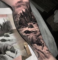 a man's arm with a bear and water scene on it