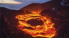 the lava is glowing red and yellow as it erupts into the air, with mountains in the background