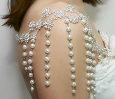 the back of a woman's body with pearls and crystals on it, as she wears