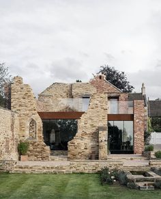 an old brick house with large windows and stone steps leading up to the front door