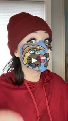 a woman with face paint on her face is looking at the camera while wearing a red hoodie