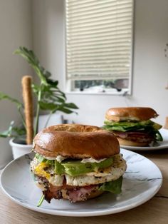 two sandwiches sitting on top of a white plate next to each other in front of a window