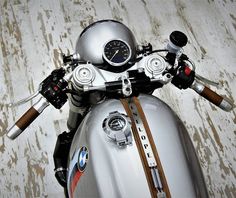 a silver motorcycle parked on top of a wooden floor next to a white wall with a clock