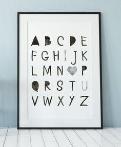 a framed black and white alphabet print on a wall