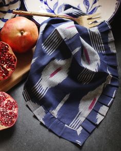 two pomegranates on a cutting board next to a knife and fork