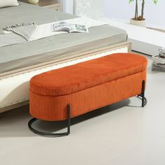 an orange bench sitting on top of a white floor next to a bed with pillows