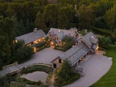 an aerial view of a large home in the middle of a wooded area with mountains in the background